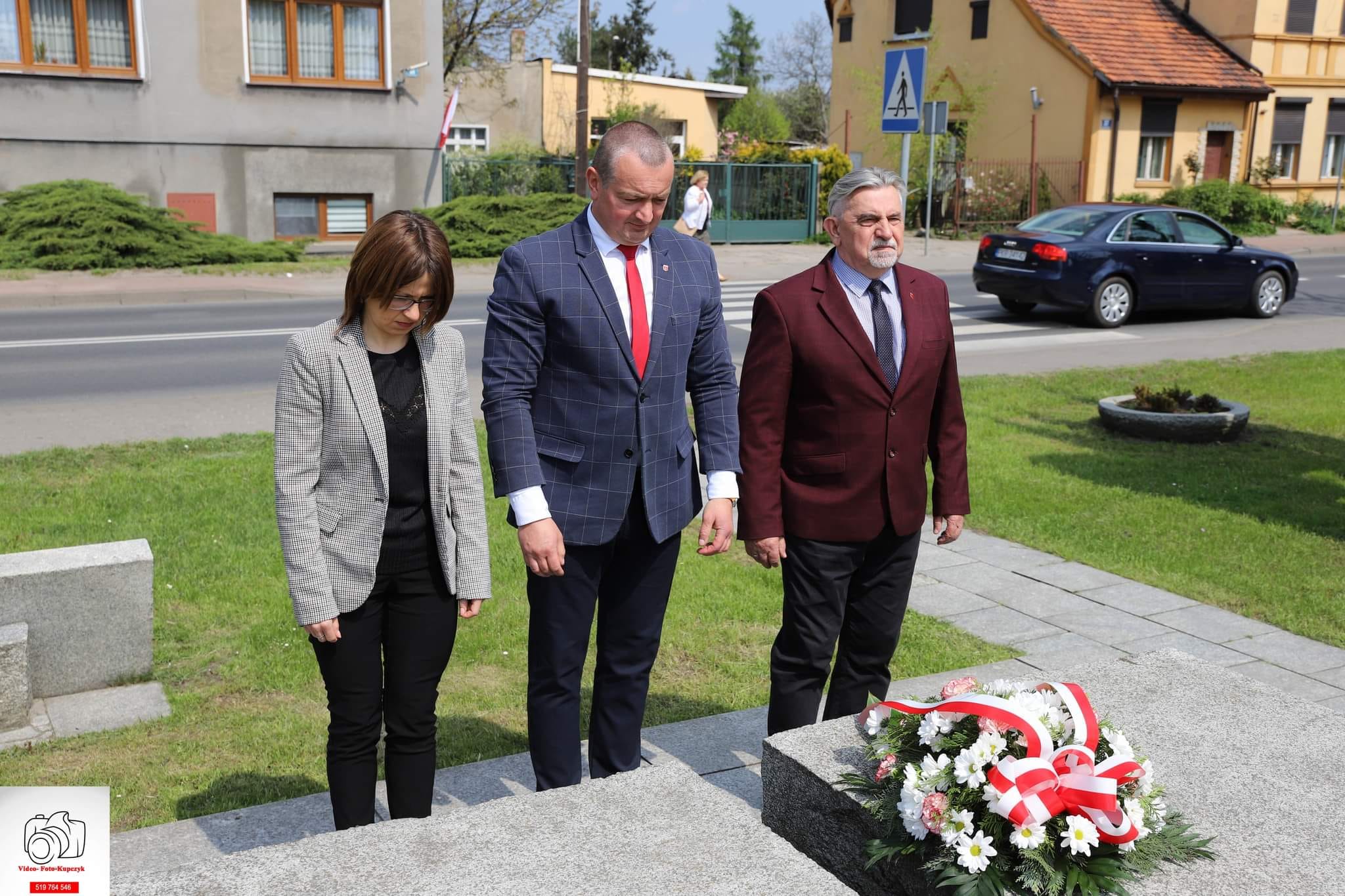 Zdjęcie na którym znajduje się Skarbnik Gminy Kobylin, Burmistrz Kobylina oraz Przewodniczący Rady Miejskiej w Kobylinie podczas złożenia kwiatów pod pomnikiem